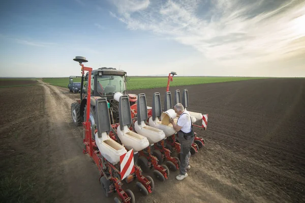 Farmer with can pouring soy seeds for sowing crops at agricultural field in spring