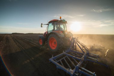 Traktör tarlada çalışıyor, tarlayı ekime hazırlıyor, tarlayı sürüyor.