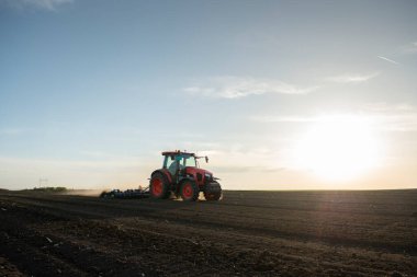 Traktör tarlada çalışıyor, tarlayı ekime hazırlıyor, tarlayı sürüyor.