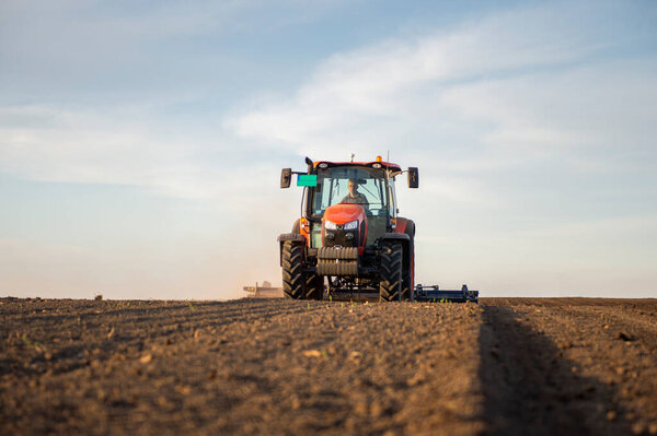 Трактор работает в поле, готовит землю для посадки, работает пашня