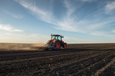 Traktör tarlada çalışıyor, tarlayı ekime hazırlıyor, tarlayı sürüyor.