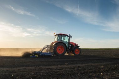 Traktör tarlada çalışıyor, tarlayı ekime hazırlıyor, tarlayı sürüyor.