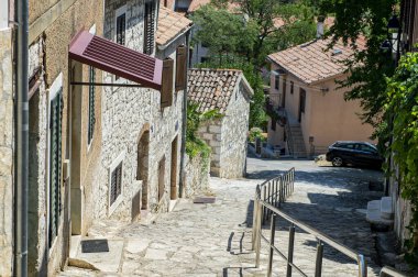 Akdeniz 'de küçük bir Cobbles caddesi. Güzel pencere panjurları. Bir evin yanında büyüyen mor çiçekler var. Açık ve güneşli bir gün. 