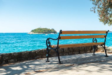 Deniz kenarında ahşap bir bank. Güneşli bir yaz günü. Rahatlamak için bir yer. Vrsar, Istrian yarımadası, Hırvatistan