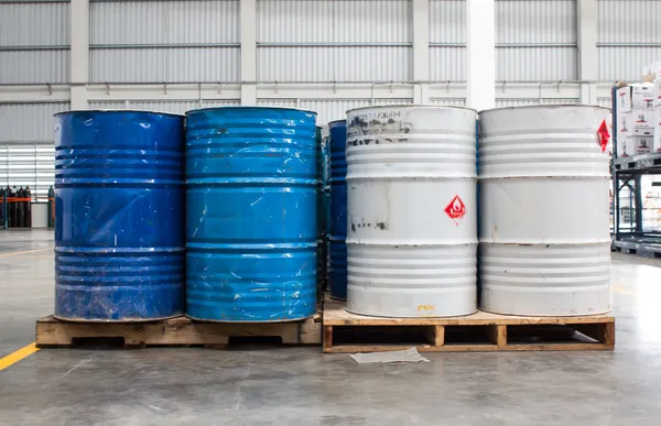 Witte container en blauwe drums op een site voor industriële opslag — Stockfoto