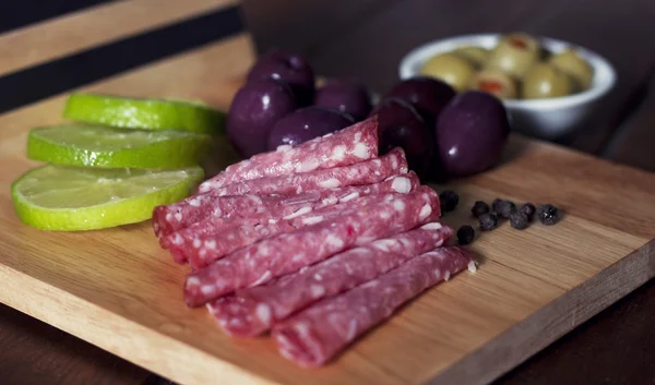 Rodajas de salami y aceitunas negras y verdes — Foto de Stock