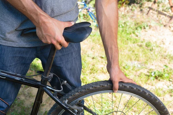 Kafkasyalı bir gencin mavi kot pantolon giydiği, gün ışığında evlerin arka bahçesinde bisiklete bindiği yakın plan görüntüsü.