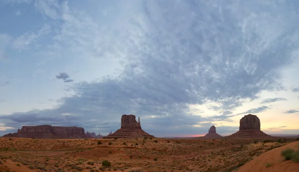 Monument Valley view at sunset with wonderfull cloudy sky and lights on mittens — Stock Photo, Image