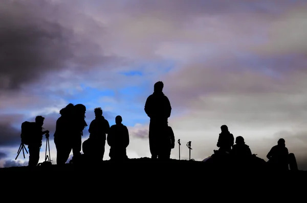 A group of trekkers black silhouette in the cloudy sky background — Stock Photo, Image