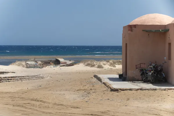 Rode Zee huis aan de oever met een verlaten boot — Stockfoto