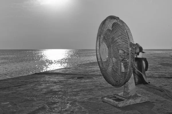 Un vieux ventilateur usagé près de la mer en noir et blanc — Photo