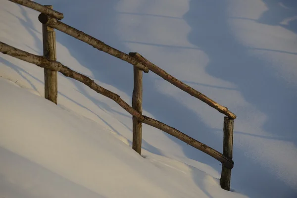 Uma cerca de madeira sobre fundo de neve branca no inverno — Fotografia de Stock