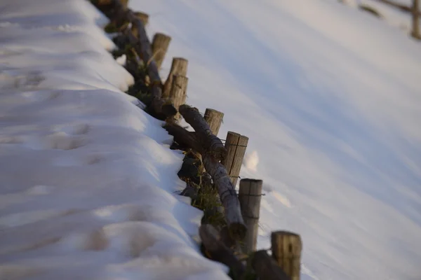 Uma cerca de madeira sobre fundo de neve branca no inverno — Fotografia de Stock