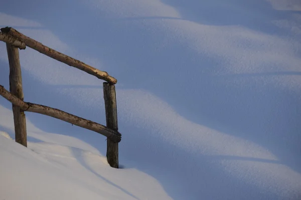 Una cerca de madera sobre fondo de nieve blanca en invierno — Foto de Stock