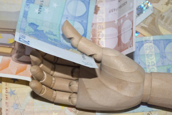 Wooden hand holding euro currency — Stock Photo, Image