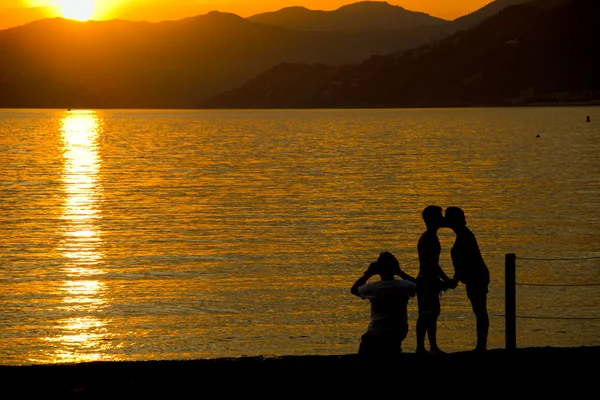 Man och kvinna whiile kyssas på sestri levante beach vid solnedgången — Stockfoto