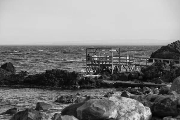 Relaxant sur une plateforme en bois sur la mer en noir et blanc — Photo