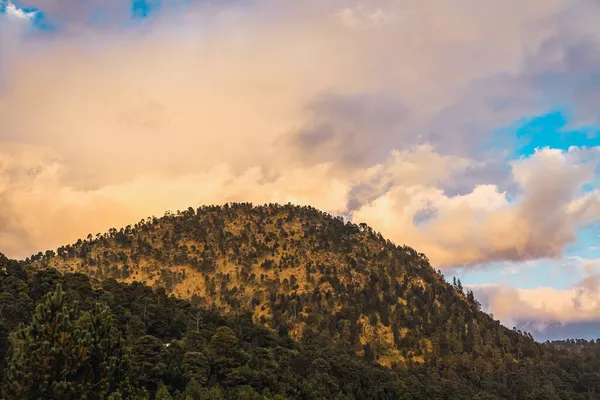 ネバダ トルカ火山近くの森の夕日の風景は 雲が赤 オレンジの色で描かれています 秋の黄土色は木々の緑と組み合わさっています — ストック写真