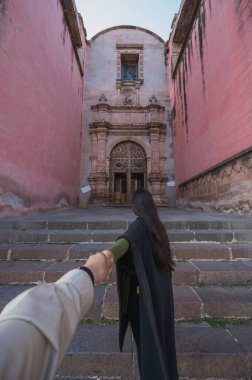 Maceracı kız, Tlalpujahua, Meksika 'nın Büyülü Kasabası' nı keşfediyor. Sokaklarına ve klasik Meksika mimarisinin kiliselerine siyah panço giyerek hayranlıkla bakıyor. POV Fotoğrafı.