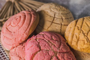 Traditional Mexican sweet bread called conchas, on a basket woven tablecloth.