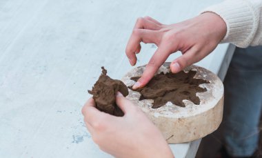 Sanatsal öğrenim atölyesinde kil şekillendiren çocuk elleri detayları.