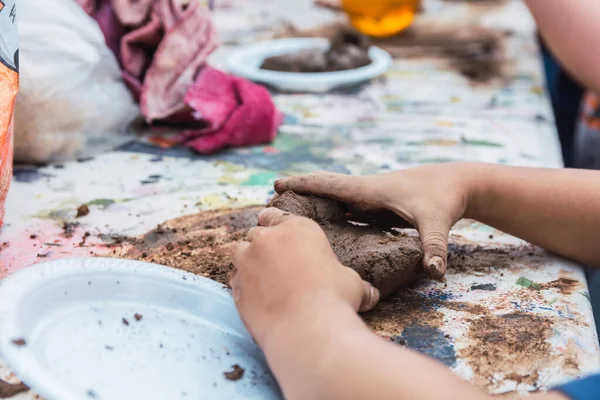 Sanatsal öğrenim atölyesinde kil şekillendiren çocuk elleri detayları.