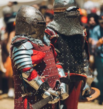 Ortaçağ şövalyelerinin çarpışması. Kendilerini savunmak için metal zırhlar, baltalar, kılıçlar ve kalkanlar kullanıyorlar..