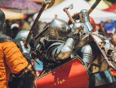 Ortaçağ şövalyelerinin çarpışması. Kendilerini savunmak için metal zırhlar, baltalar, kılıçlar ve kalkanlar kullanıyorlar..