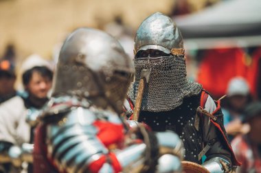 Ortaçağ şövalyelerinin çarpışması. Kendilerini savunmak için metal zırhlar, baltalar, kılıçlar ve kalkanlar kullanıyorlar..