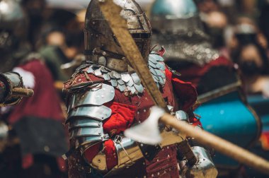 Ortaçağ şövalyelerinin çarpışması. Kendilerini savunmak için metal zırhlar, baltalar, kılıçlar ve kalkanlar kullanıyorlar..