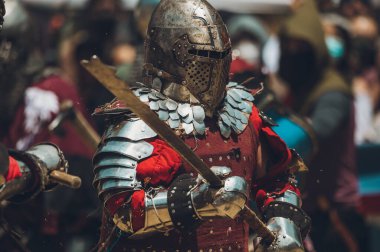 Ortaçağ şövalyelerinin çarpışması. Kendilerini savunmak için metal zırhlar, baltalar, kılıçlar ve kalkanlar kullanıyorlar..