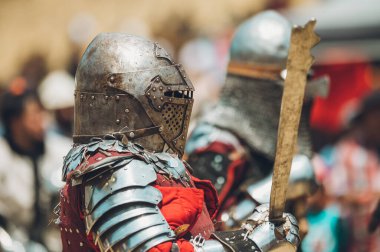 Ortaçağ şövalyelerinin çarpışması. Kendilerini savunmak için metal zırhlar, baltalar, kılıçlar ve kalkanlar kullanıyorlar..