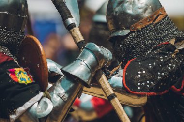 Ortaçağ şövalyelerinin çarpışması. Kendilerini savunmak için metal zırhlar, baltalar, kılıçlar ve kalkanlar kullanıyorlar..