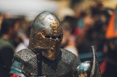 Ortaçağ şövalyelerinin çarpışması. Kendilerini savunmak için metal zırhlar, baltalar, kılıçlar ve kalkanlar kullanıyorlar..