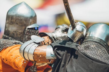 Ortaçağ şövalyelerinin çarpışması. Kendilerini savunmak için metal zırhlar, baltalar, kılıçlar ve kalkanlar kullanıyorlar..