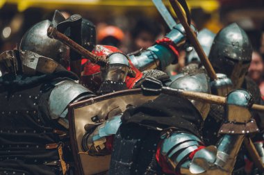 Ortaçağ şövalyelerinin çarpışması. Kendilerini savunmak için metal zırhlar, baltalar, kılıçlar ve kalkanlar kullanıyorlar..
