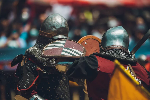 Ortaçağ şövalyelerinin çarpışması. Kendilerini savunmak için metal zırhlar, baltalar, kılıçlar ve kalkanlar kullanıyorlar..