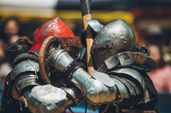 Ortaçağ şövalyelerinin çarpışması. Kendilerini savunmak için metal zırhlar, baltalar, kılıçlar ve kalkanlar kullanıyorlar..