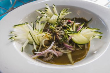 Aguachile de alabalık, tipik Meksika yemeği, salatalık, mor soğan, serrano biber sosu ve çiğ balığı pişiren limonla yıkanmış. Mavi bir masada.