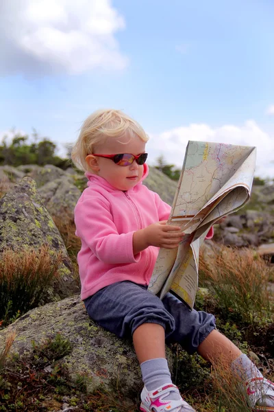 Barn flicka sitter på berget med karta — Stockfoto