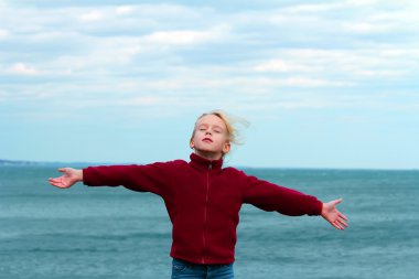 Teenager girl arms raised enjoying the fresh ocean air.