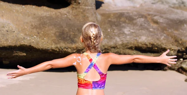 Girl on the beach with sunscreen lotion — Stock Photo, Image