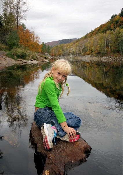 Girl sitting on the stone near the river — Stock Photo, Image