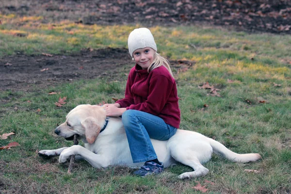 Flicka som leker med sin hund i park Stockbild