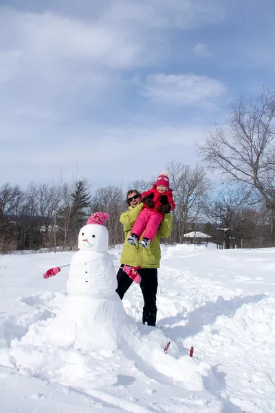 Pai feliz e sua filha criança bonito construindo o boneco de neve — Fotografia de Stock