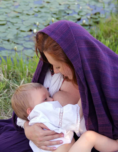 Молодая мать с платком на голове ухаживает за своим малышом — стоковое фото