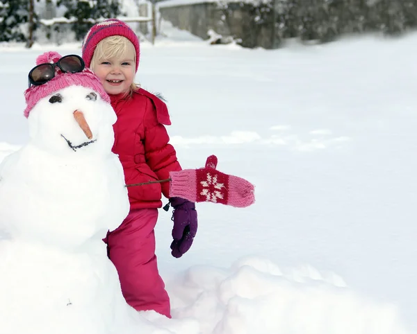 Adorable niña jugando con el muñeco de nieve —  Fotos de Stock