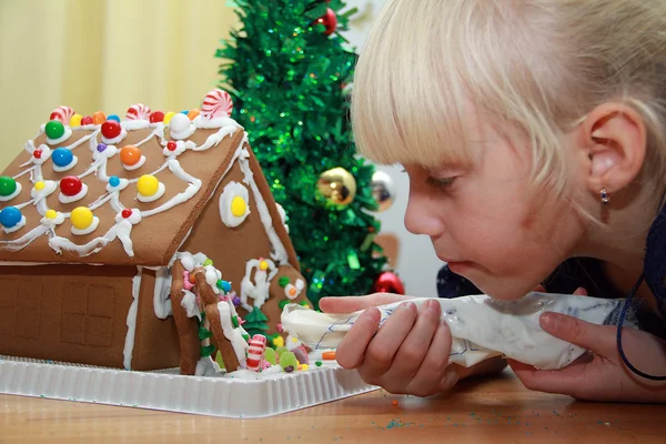 Flickan dekorera Pepparkakshuset Royaltyfria Stockfoton