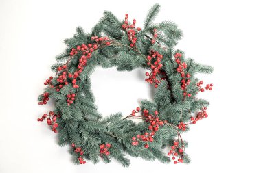Kırmızı böğürtlenlerin dekoratif ladin dallarından toplanan Noel çelengi beyaz stüdyo arka planında. Metin için yeri olan Noel çerçevesi.