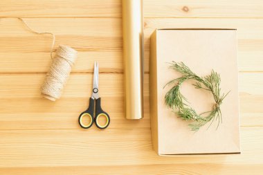 Orijinal, çevre dostu Noel hediyeleri paketi dışında. Adım adım talimat veriyorum. DIY. Masada el işi kutusu, kırbaç, yeşil dal çelenk, ambalaj kağıdı, makas var. Üst Manzara. Adım 1.